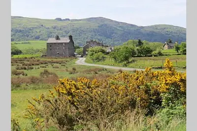 a field with a house and a road in the middle at The Little Boat House in Talsarnau