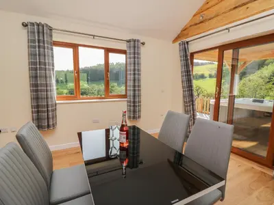 a dining room with a table and chairs and windows at Ploony Hill Cabin in Knighton
