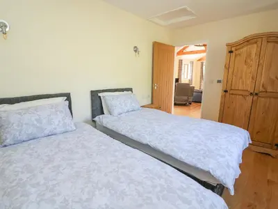 a bedroom with two beds and a wooden cabinet at Ploony Hill Cabin in Knighton
