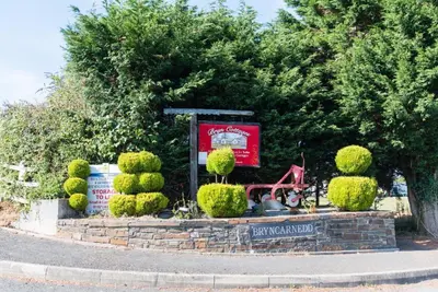 a sign in a garden with bushes and trees at The Dairy in Aberystwyth