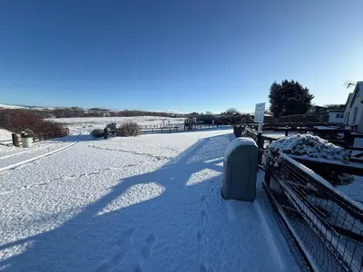 a snow covered street with a fence with a mailbox at The Dairy in Aberystwyth