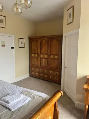 a bedroom with a bed and a wooden cabinet at The Lion Hotel in Llansantffraid-ym-Mechain