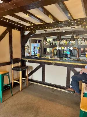 a bar in a pub with a person sitting at it at The Lion Hotel in Llansantffraid-ym-Mechain