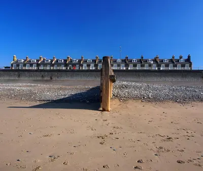 a wooden post on the beach with a building in the background at Snowdonia Hideaway in Tywyn