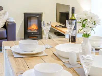 a wooden table with plates and wine glasses and a fireplace at Ty Arth - Uk31652 in New Quay