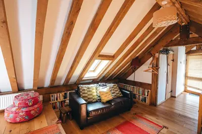 a living room with a leather couch and wooden ceilings at the garden room in Shrewsbury