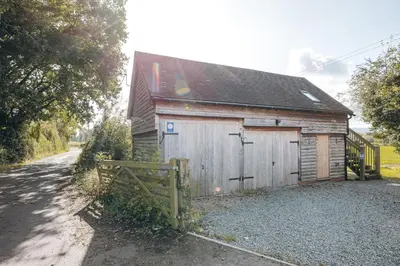 a small wooden building with a fence next to a road at the garden room in Shrewsbury