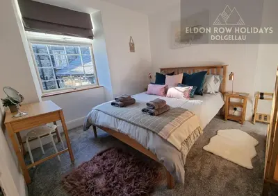 a bedroom with a bed and a desk and a window at Eldon Row - Stylish Character Apartments - Central Location 1 & 2 bed available in Dolgellau
