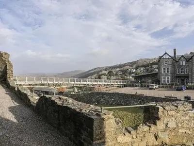 a stone wall with a building and a street at Harlech Apartments - Efnisien in Harlech