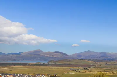 a view of a field with mountains and a body of water at Harlech Apartments - Efnisien in Harlech