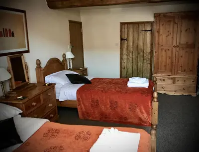 a bedroom with two beds and a dresser at The White Horse Inn, Clun in Clun