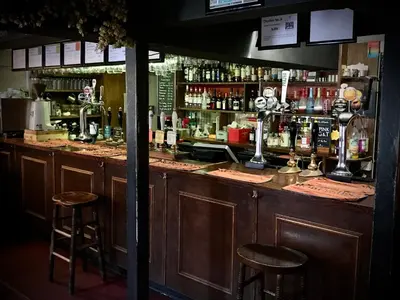 a bar with two bar stools and bottles of alcohol at The White Horse Inn, Clun in Clun