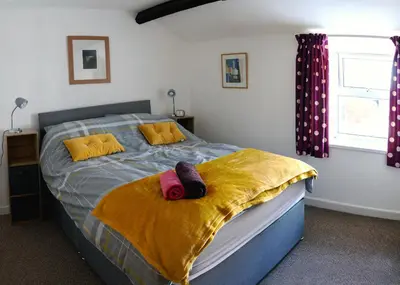 a bedroom with a bed with yellow and purple sheets at Bwthyn Gweilch in Machynlleth