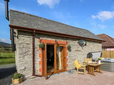 a small stone house with a table and a table at Tegfan Barn in Rhayader