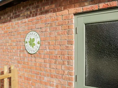 a brick wall with a clock on the side of a building at Conkers' Cottage in Church Stretton