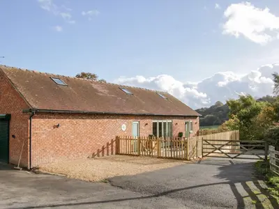 a brick building with a gate and a fence at Conkers' Cottage in Church Stretton