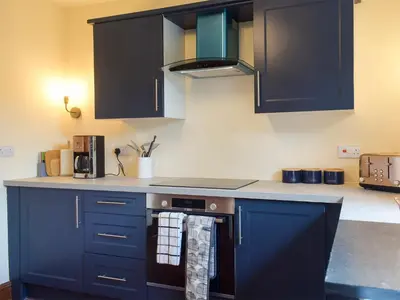 a kitchen with blue cabinets and a stove top oven at Llantysilio Lodge in Llangollen