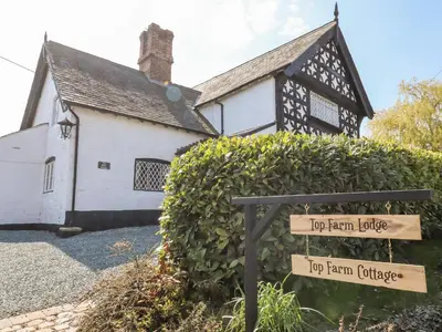 a house with a sign in front of a hedge at Top Farm Cottage in Oswestry