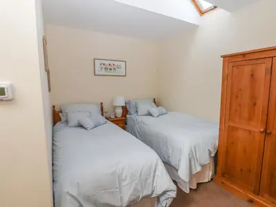 a bedroom with two beds and a wooden cabinet at Top Farm Lodge in Oswestry