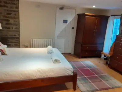a bedroom with a bed and a dresser and a door at Bryncarnedd Farmhouse in Aberystwyth