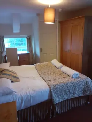 a bedroom with a large bed with white sheets at Bryncarnedd Farmhouse in Aberystwyth