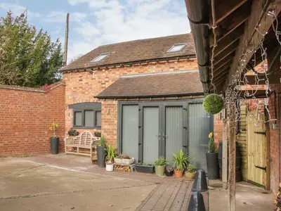 a garage with grey doors and potted plants at Bank House Barn in Shrewsbury