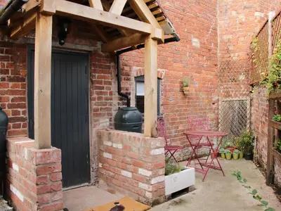 a patio with a black door and a brick wall at Bank House Barn in Shrewsbury