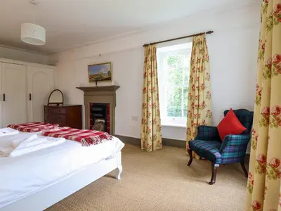 a bedroom with a bed and a chair and a window at Mor Edrin in Talsarnau