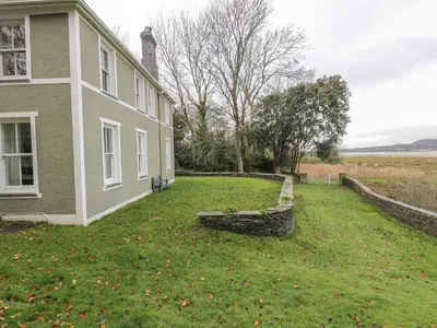 a house with a grass yard next to a building at Mor Edrin in Talsarnau