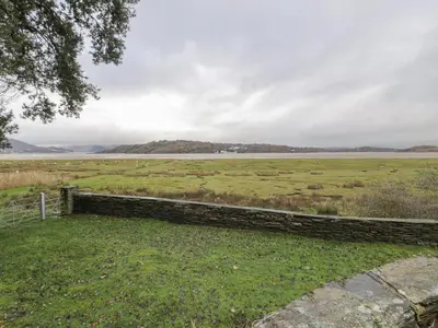 a field with a fence and a body of water at Mor Edrin in Talsarnau