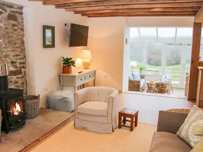 a living room with a fireplace and a chair at Brynlikky Cottage in Bucknell