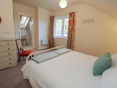 a bedroom with a bed and a chair and a window at Brynlikky Cottage in Bucknell