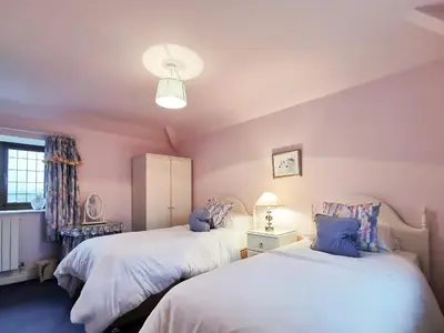 two beds in a room with pink walls at Holly Barn in Selattyn