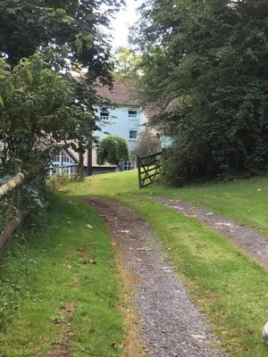 a dirt road in front of a white house at The Hillis Farmhouse - 6 Bed - Sleeps 11 - Pets in Brecon