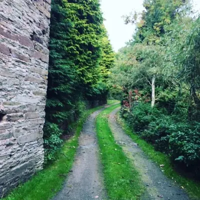 a dirt road next to a brick wall at The Hillis Farmhouse - 6 Bed - Sleeps 11 - Pets in Brecon