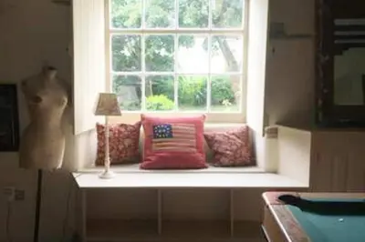 a window seat with pillows in front of a window at The Hillis Farmhouse - 6 Bed - Sleeps 11 - Pets in Brecon