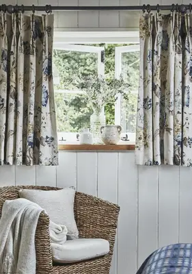 a room with a chair and a window with curtains at Tan Llan in Dolgellau