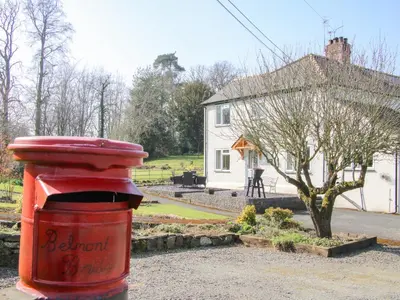 a red trash can in front of a white house at Belmont Bridge in Oswestry