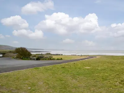 a road leading down to a beach with the ocean at Plas Bach in Llanon