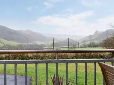a view from a balcony of a field and mountains at Ty Nant - Uk32239 in Lower Chapel