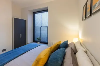 a bedroom with a large bed with blue pillows at New central seafront apartment- stunning sea views in Aberystwyth