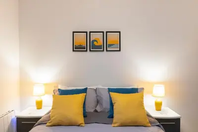 a bedroom with two lamps and a bed with yellow pillows at New central seafront apartment- stunning sea views in Aberystwyth