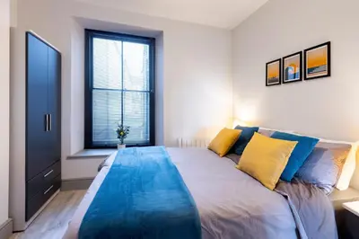 a bedroom with a large bed with yellow and blue pillows at New central seafront apartment- stunning sea views in Aberystwyth