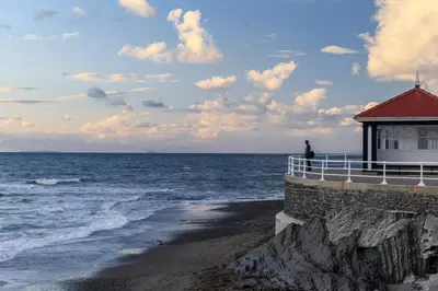 a man standing on the edge of a building near the ocean at New central seafront apartment- stunning sea views in Aberystwyth