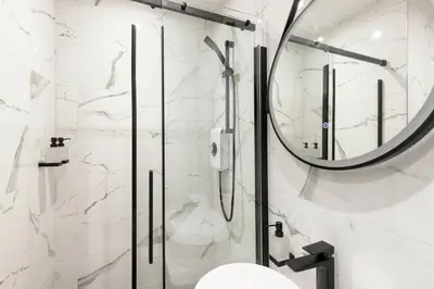 a bathroom with a shower and a mirror at New central seafront apartment- stunning sea views in Aberystwyth