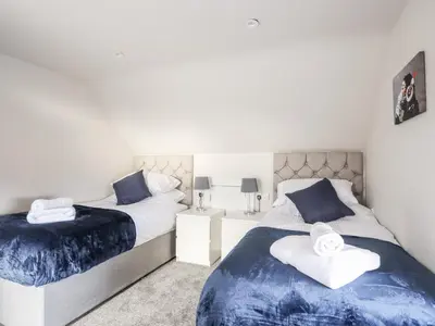 a bedroom with two beds with blue and white sheets at Drovers Barn in Corwen