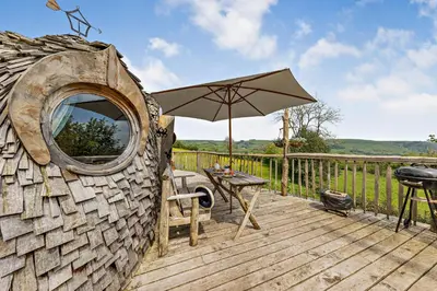 a wooden deck with a table and an umbrella at HOBLEY House Holiday in Craven Arms