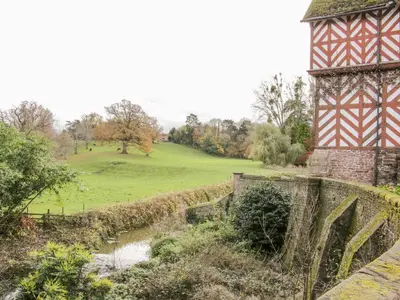 a tower and a bridge next to a river at The Generals Quarters at Pitchford Estate in Shrewsbury