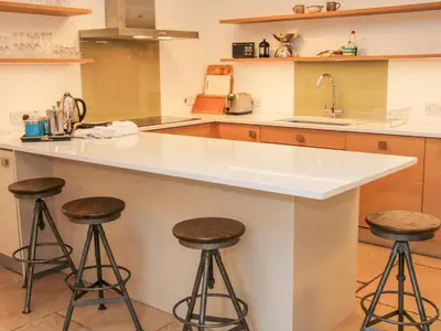 a kitchen with two bar stools and a sink at Treehouse Barn at Pitchford Estate in Shrewsbury
