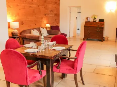 a dining room with a wooden table and red chairs at Treehouse Barn at Pitchford Estate in Shrewsbury